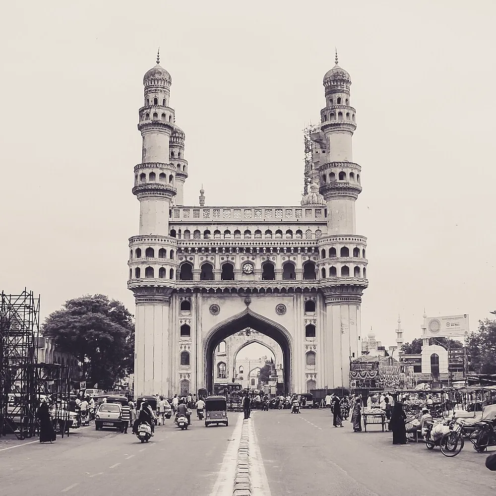 The Charminar in Hyderabad in black and white, seen down a busy street.
